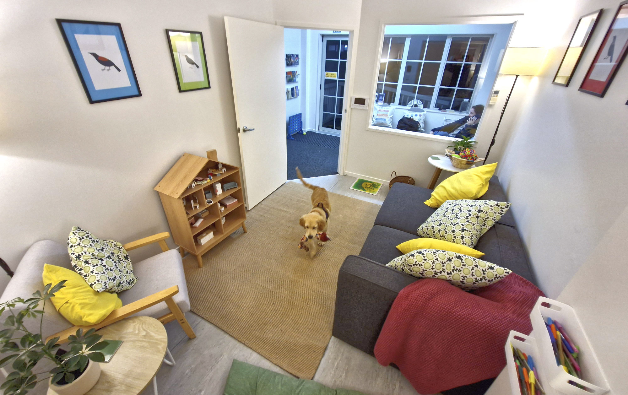 The Kinder Minds playroom, with Neve carrying a toy across the rug